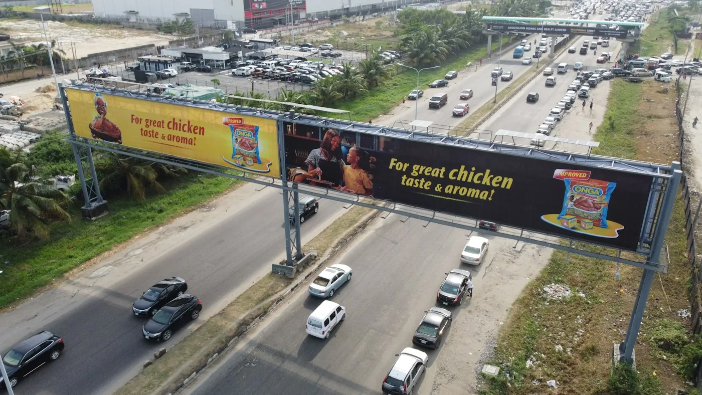 Large brand billboards on a highway gantry — representative service image