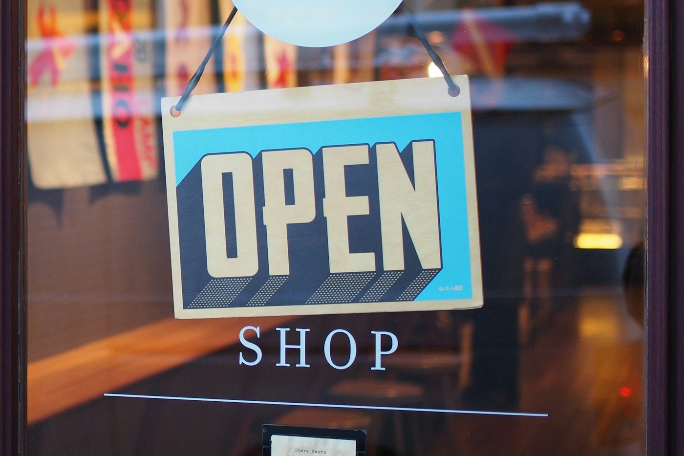 Retail shop signage hanging on a store glass door — representative image